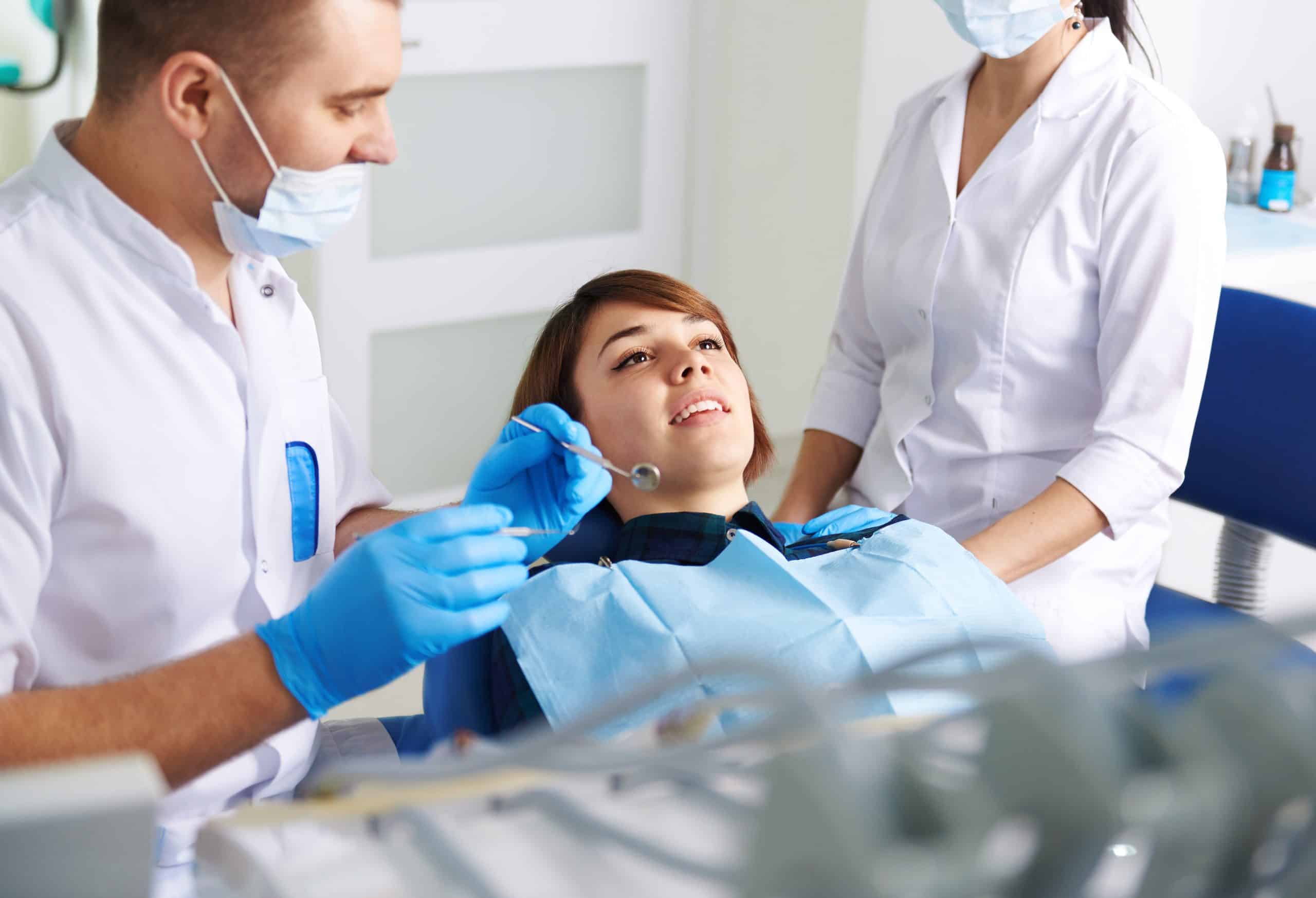 Cosmetic Dentist San Antonio and assistant inspecting woman patient during dental procedure